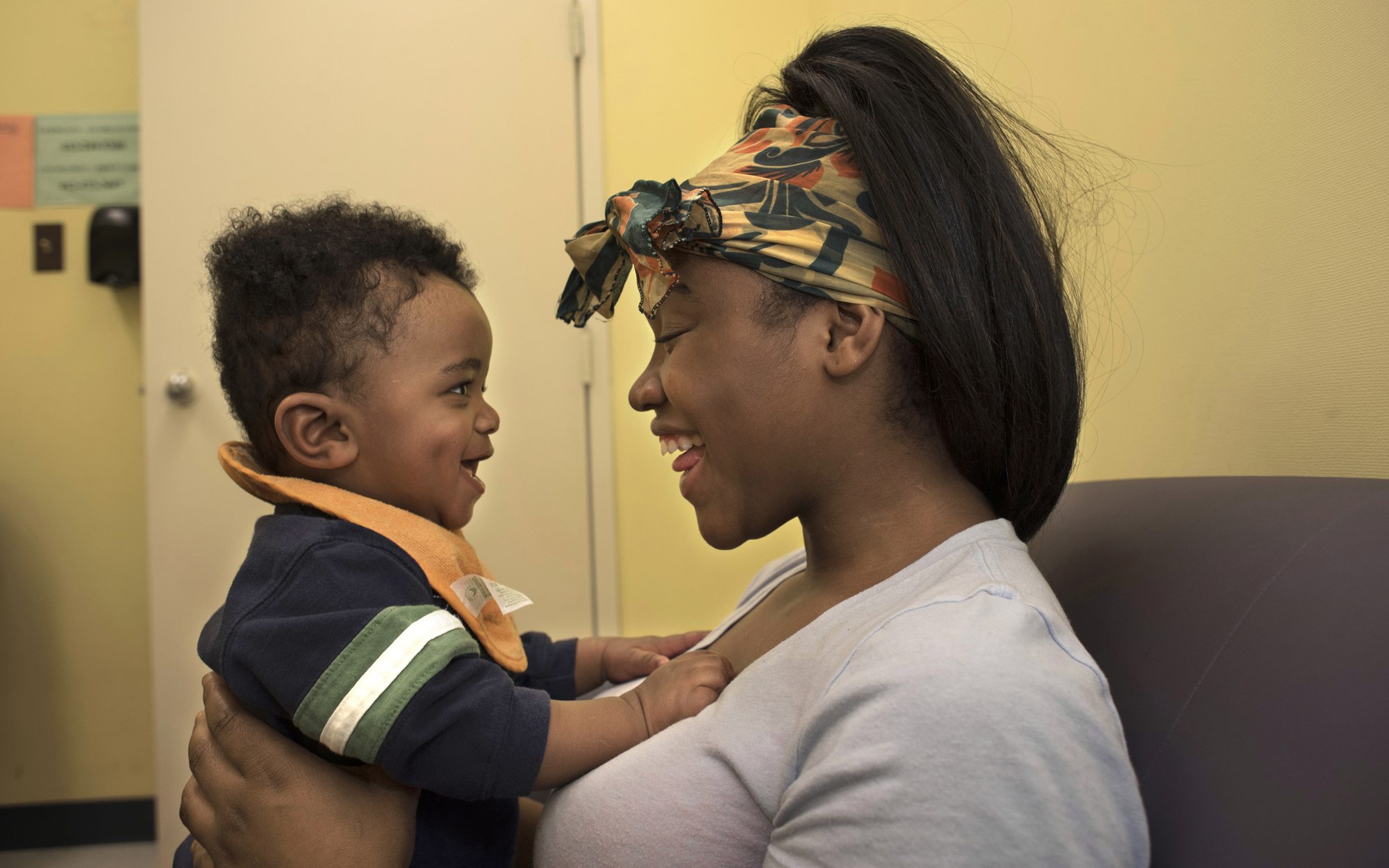 Tyneisha Wilder sings to her son Tayden, age 8 months, while bouncing him on her lap during a supervised visit at CYF Lexington office in Point Breeze. Wilder is permitted to visit with Tayden twice a week after school for two hours. (Photo by Martha Rial/PublicSource)