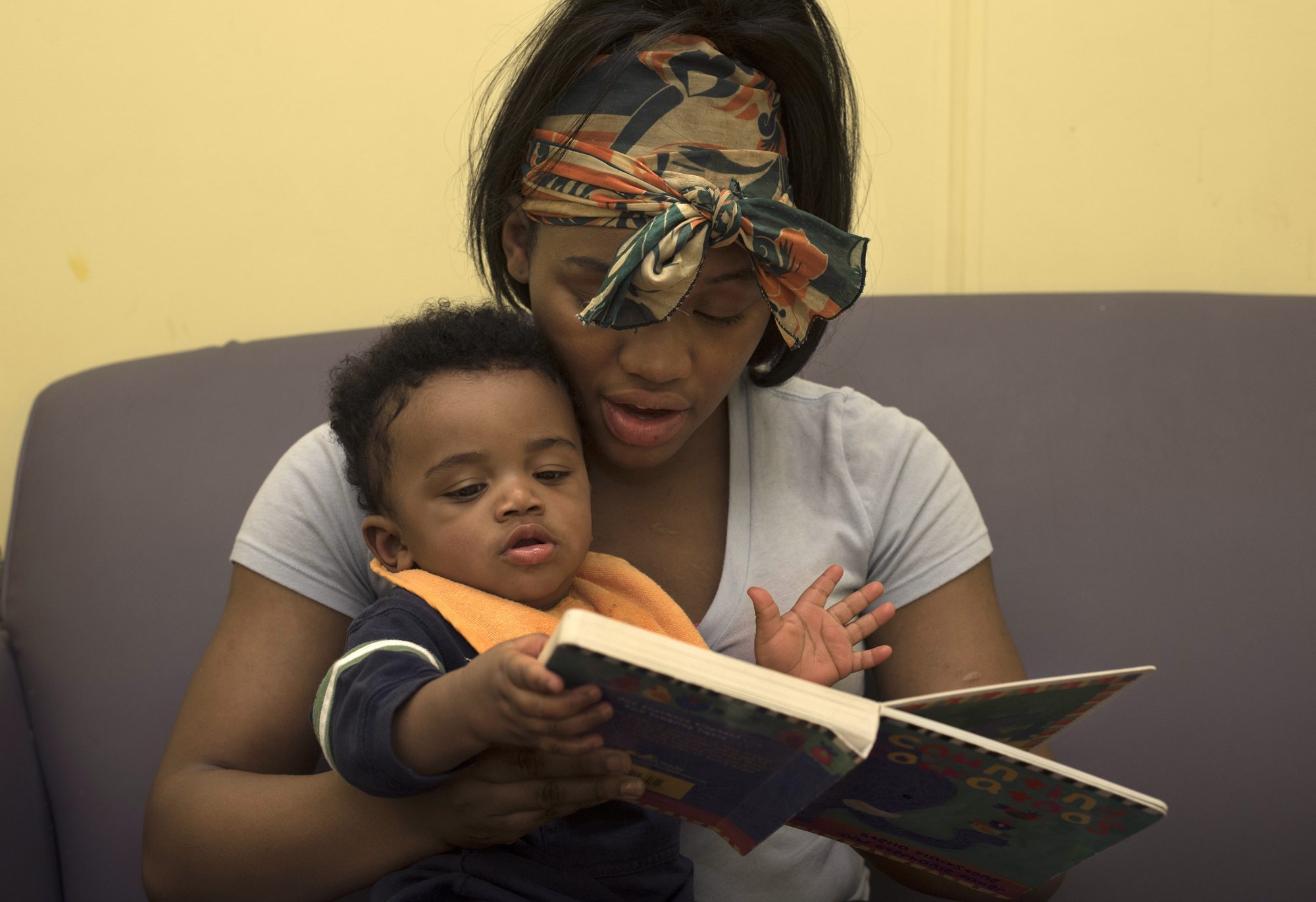 Tyneisha Wilder, 18, reads to her son Tayden, age 8 months, during a supervised visit at CYF Lexington office in Point Breeze. Tayden was four days old when he was taken from Tyneisha and put into foster care. (Photo by Martha Rial/PublicSource)