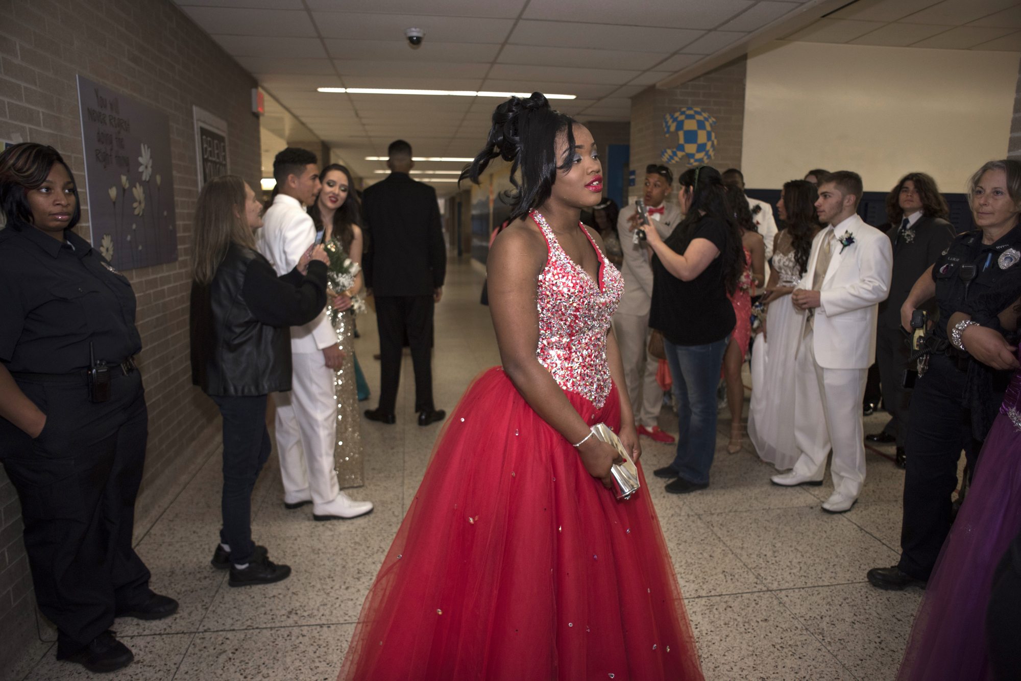 Tyneisha Wilder watches her friend and prom date pose for photographs in the lobby of East Allegheny High School in North Versailles before Prom. Wilder will graduate in June. (Photo by Martha Rial/PublicSource)